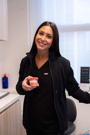 Madison Dental team member holding dental model explaining treatment benefits through patient education during consultation appointments.