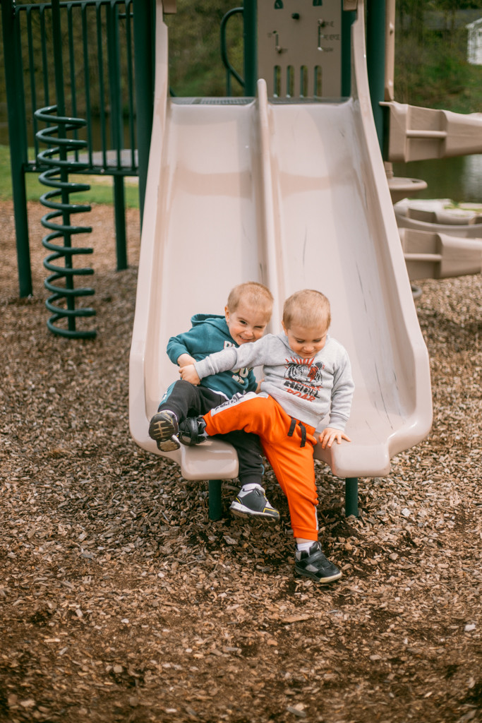 Twin siblings playing on the playground at the park during a family lifestyle photography session.