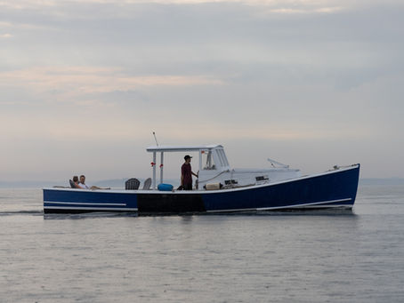 A blue and white lobster boat cruising through Belfast, Maine Harbor