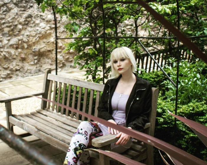Lady with blonde hair sat on bench.PNG