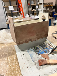 Large slab-built ceramic vessel in progress with layered clay surfaces and visible construction lines.