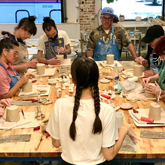 Students handbuilding pottery at a worktable in a Los Angeles ceramics studio.