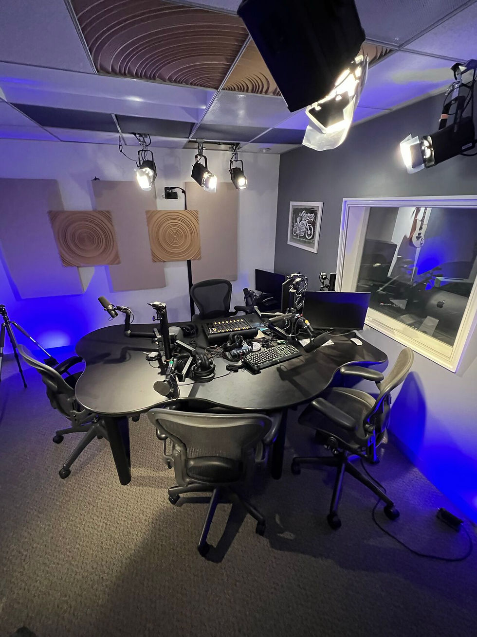 Podcast studio with Shure SM7B microphones, Apple computers, lighting equipment, sound proofing, audio recording setup. 