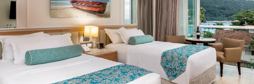 Resort room with two beds, teal accents, balcony and ocean view