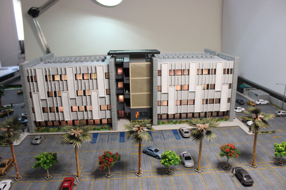 Acceso principal con señalética y vegetación en maqueta arquitectónica de S21 Corporativo.