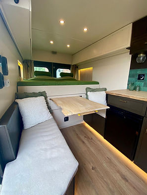 Gezellige zit- en eethoek in campervan met massief houten tafel en opbergruimte