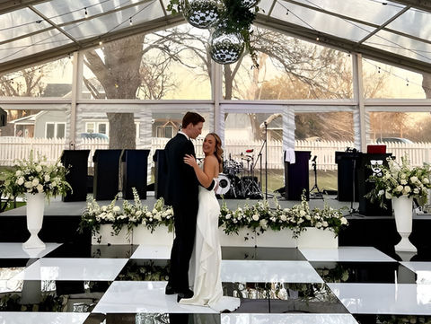 Stunning black and white wedding dance floor with a high-gloss finish, set under a beautifully decorated marquee with fairy lights.