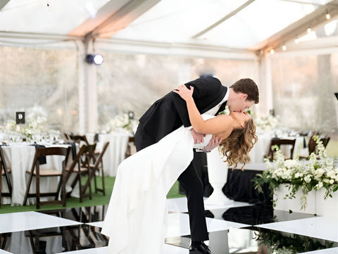 Elegant black and white chequered gloss dance floor at a luxury wedding, with a couple's first dance under a marquee with fairy lights.