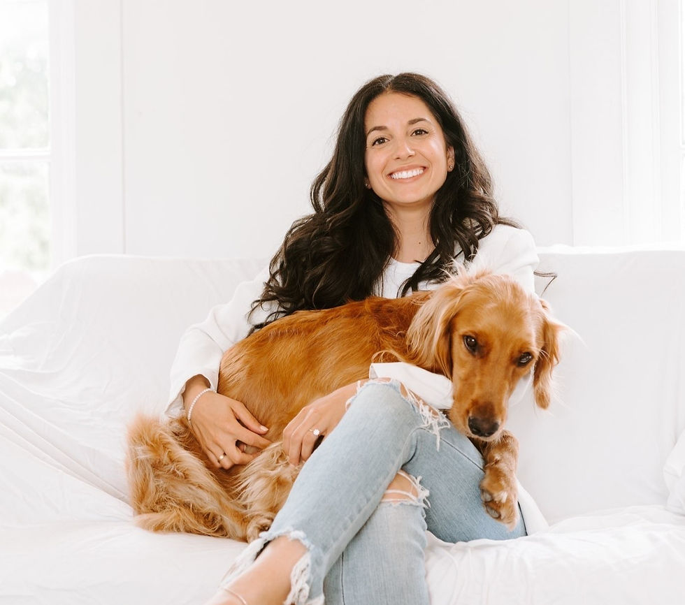 Smiling woman sitting on a white couch with a golden retriever on her lap