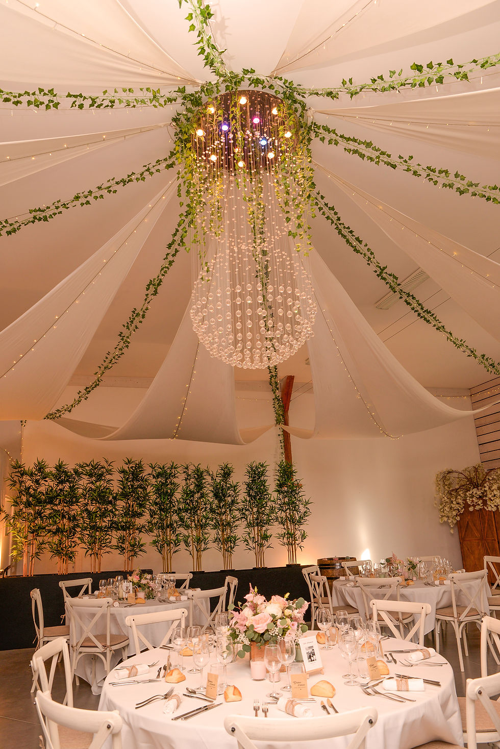 Décoration de la Salle Prestige de La Combe d'Été avec draperies au plafond, lustre majestueux et tables de banquet dressées.