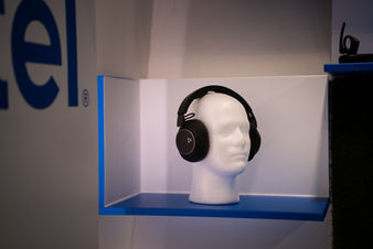 Headphones displayed on a mannequin head in a branded blue-lit box, product photography