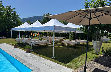 Location de barnums avec tables et bancs installés dans un jardin près d’une piscine