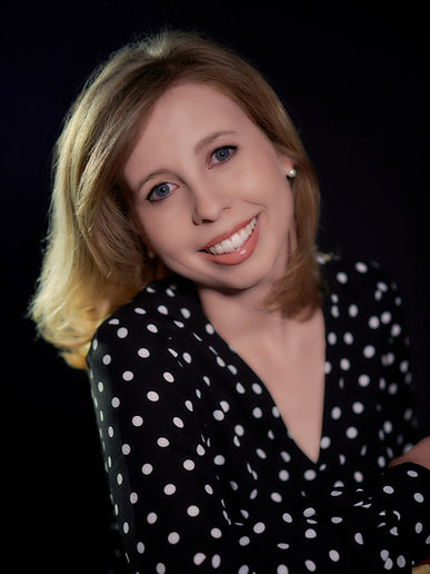 Portrait of smiling pianist Bridget Hough in polka-dot dress against black background.