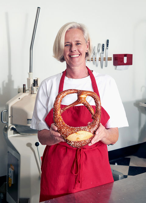 Founder holding oversized finished pretzel in bakery portrait