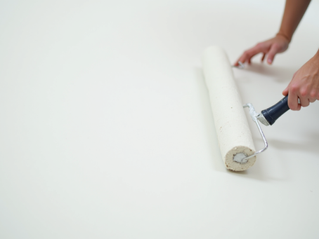 Eye-level view of a painter rolling white paint on a smooth wall