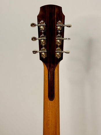 The rear of a guitar headstock veneered with East Indian Rosewood which extends down the back of the neck to the third fret position. Chrome, Waverly open geared tuners are installed.