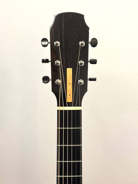 The headstock of a finished guitar with chrome tuners, Ebony faceplate and tuner knobs, and Honduran Mahogany truss rod cover.