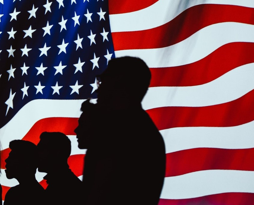 People silhouetted against American Flag Photo by Brett Sayles from Pexels