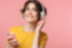 Woman wearing pink headphones while holding her iPhone 7 in pink case