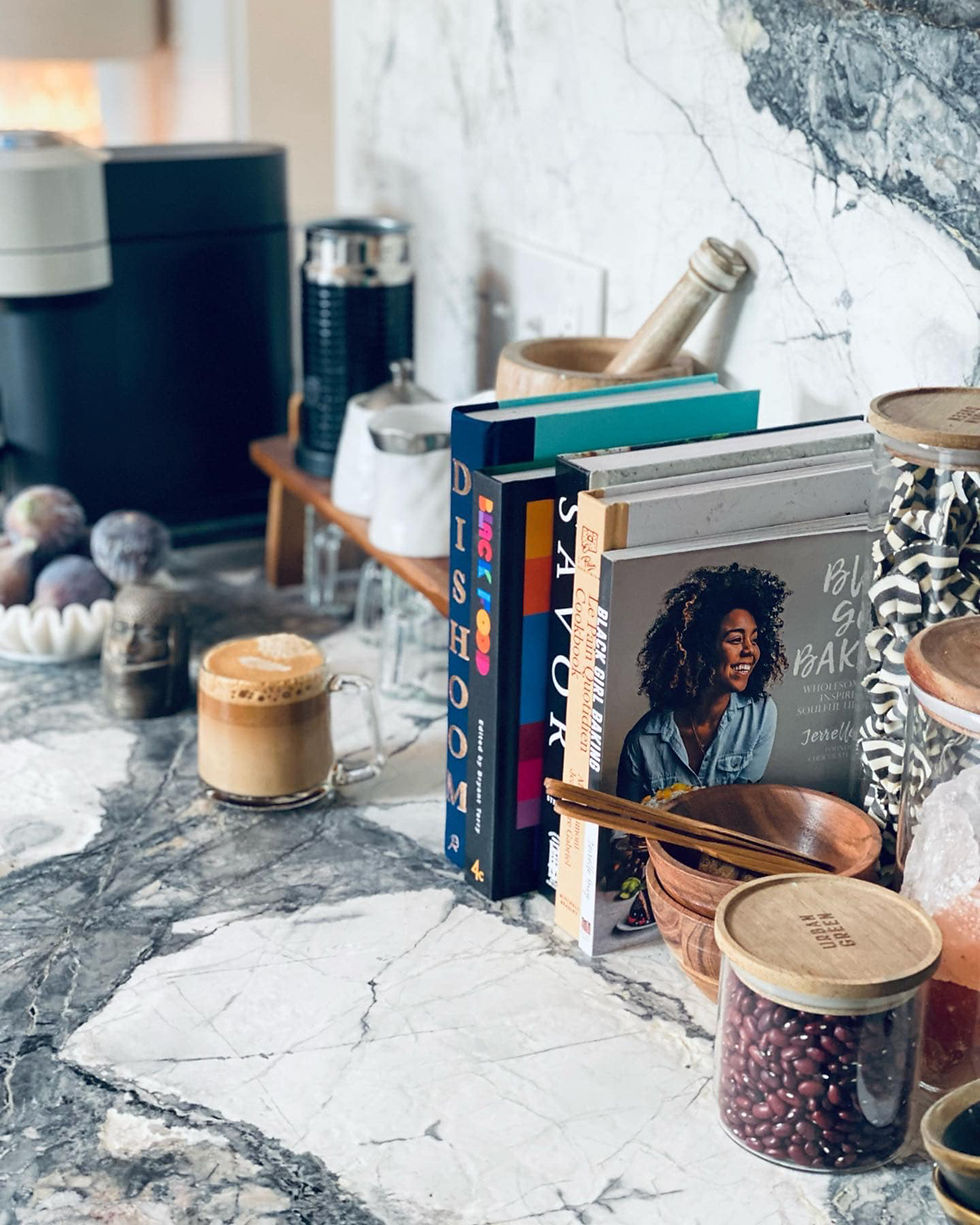 Gray stone countertop with books, coffee maker and esthetic decor on top.