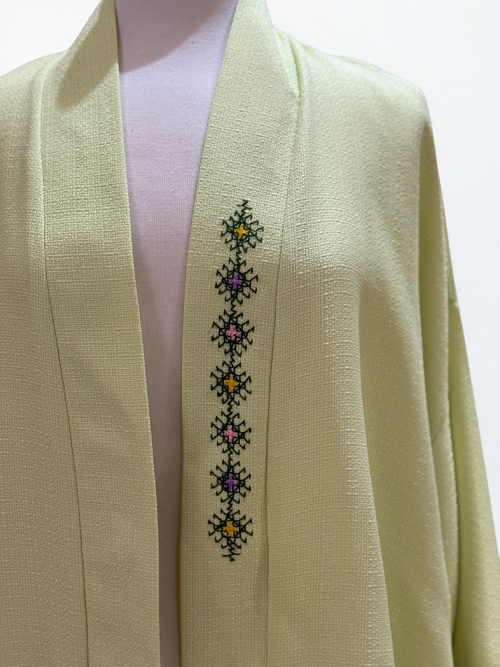 Veste vert clair avec broderie. Alghorza détail de vêtement élégant et coloré.