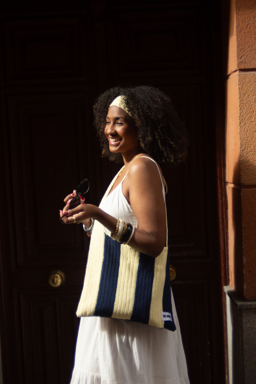 Modelo sonriendo en un portal con el bolso de ganchillo hecho a mano THE LUCKY ME BAG Lemon Coast