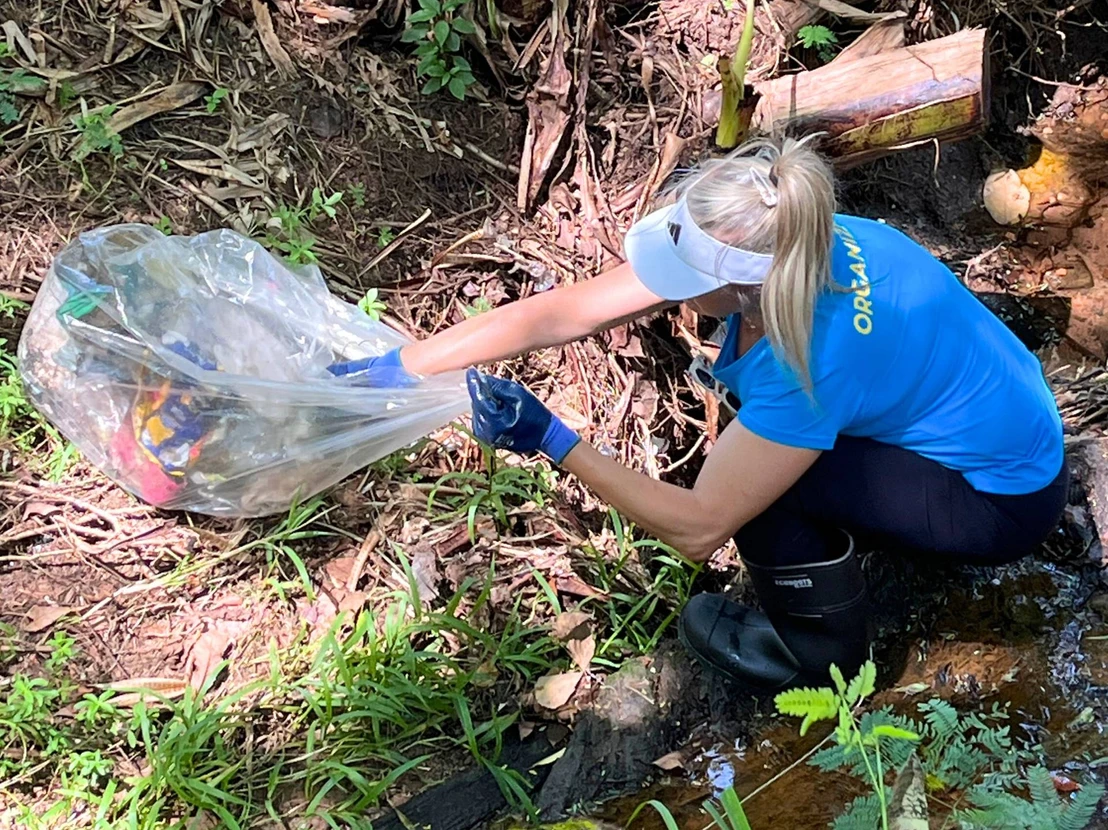 Voluntária retirando resíduos plásticos do Córrego Tijuco Preto