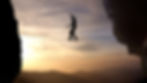 Silhouette of a person balancing on a tightrope between cliffs at sunset. A scenic sky and distant mountains create a dramatic backdrop.