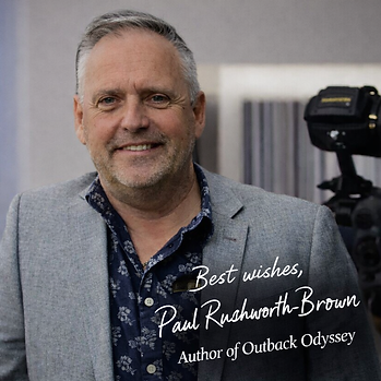 Portrait of Australian historical novelist Paul Rushworth-Brown standing beside a video camera, wearing a grey blazer and smiling. Text overlay reads: "Best wishes, Paul Rushworth-Brown, Author of Outback Odyssey." paul-rushworth-brown-best-wishes-outback-odyssey-author.jpg