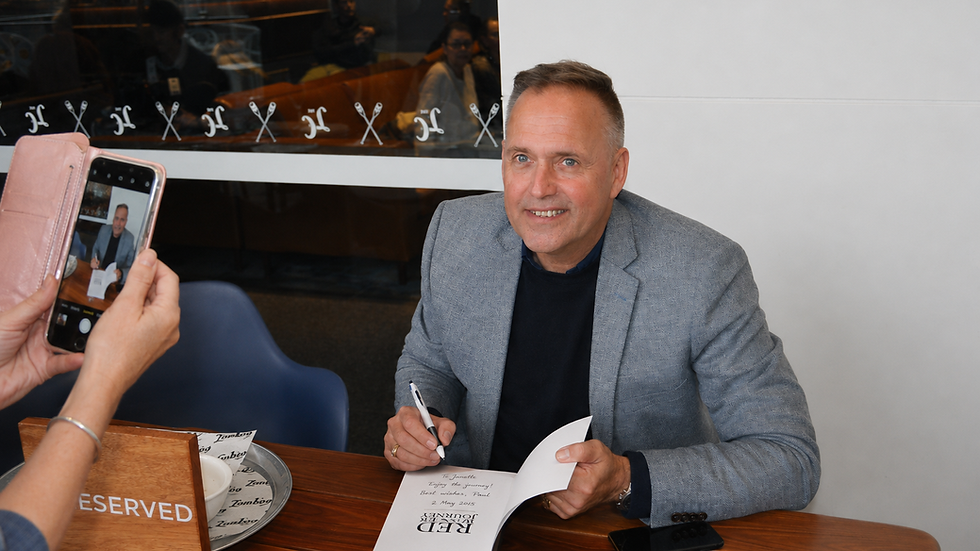 Paul Rushworth-Brown signing copies of Red Winter Journey for readers during a book signing event.