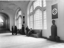 Interior of a public building in Nazi Germany during World War II, illustrating the atmosphere of ideological control and surveillance.