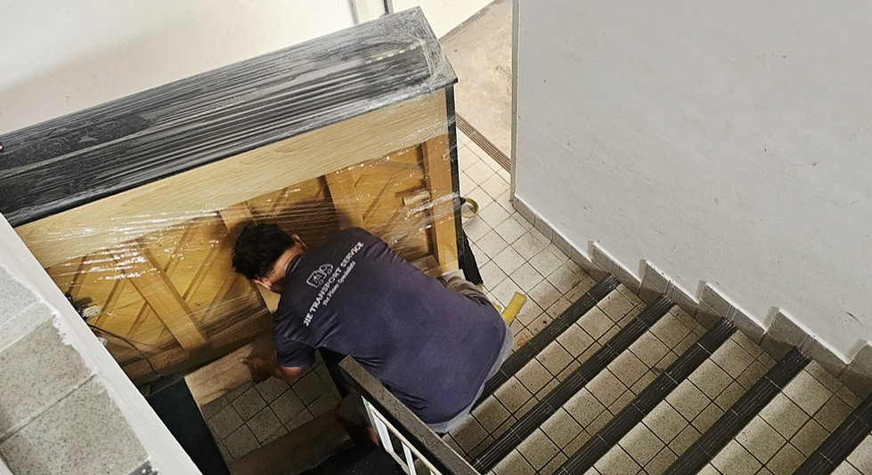 Professional piano movers carrying upright piano safely up a staircase in Singapore residential buil