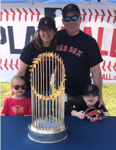 The Murphy family smile behind the 2013 Red Sox World Series trophy. Georgia, Susan, Peter and Donovan smile together wearing baseball attire.