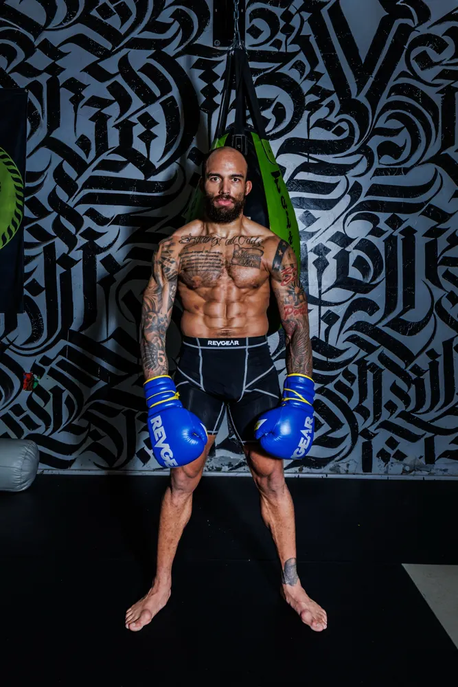 AJ in boxing gloves against a mural wall