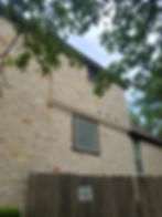 The glass block window is exposed and has no covering. The first-floor window opening is also uncovered.