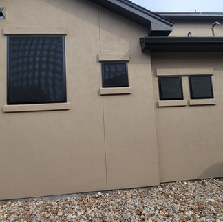 Multiple black framed solar screens on beige stucco home in Cedar Park TX