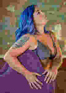 Blue hair fades into pastel colors on the model showing a skull tattoo on her upper arm and various feminine tattoos throughout.