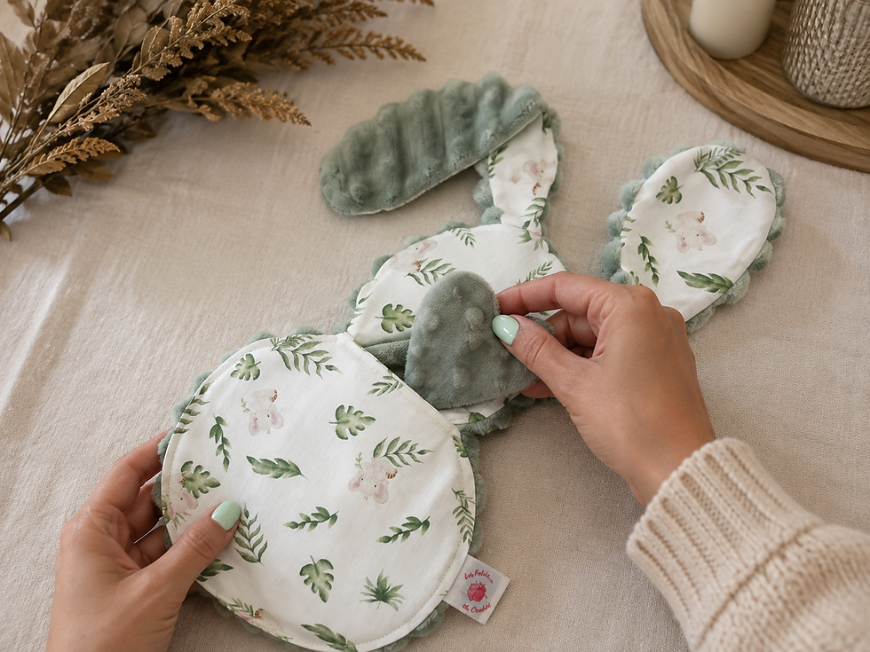 Mains glissant le petit cœur en tissu vert dans la poche du doudou lapin, préparatifs avant le départ à la maternité