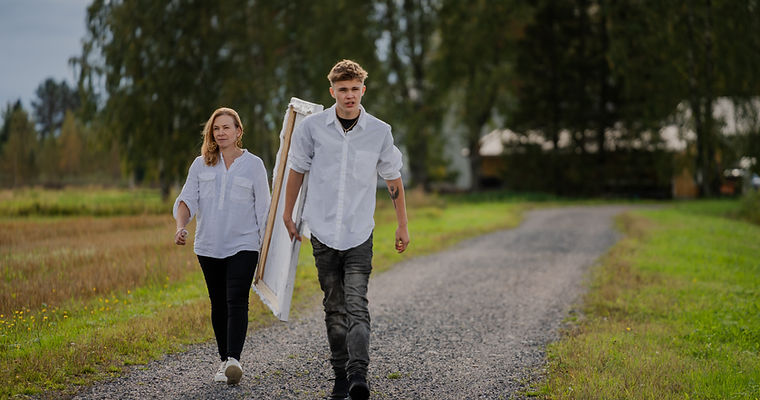 Young man carries canvas, walks with woman on path