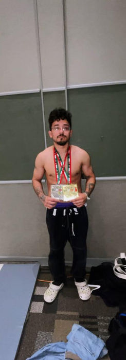 Isiel, personal trainer and MMA coach at Ampersand Fitness, holding two championship medals after a martial arts competition