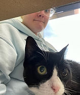 A young woman sitting at a table with her cat on her lap