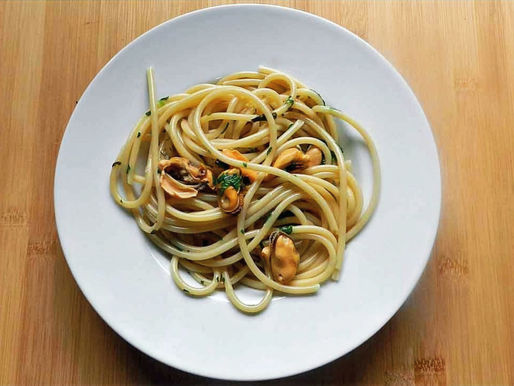 Ein Teller voller Pasta, die mit Miesmuscheln gemischt ist.