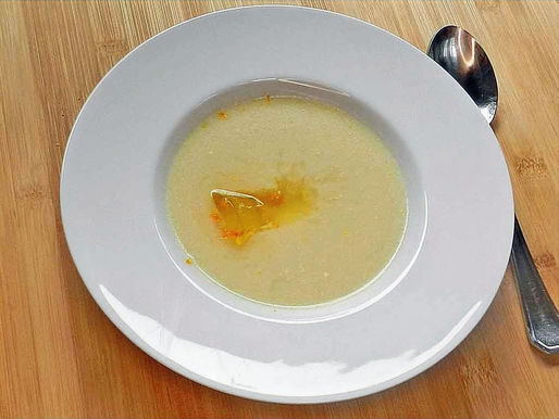 Ein Teller helle Spargelsuppe, in der gelbes Safran-Gelee schmilzt.