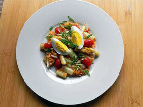 Ein Salat aus roten Linsennund weißem Spargel ist verzehrbereit angerichtet.