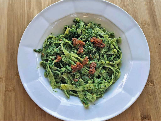 Ein teller Pasta, die mit Pesto von Grünkohl gemischt ist.