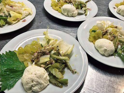 Auf mehreren Tellern wird ein Salat aus Sellerie, Trauben und Frischkäse angerichtet.
