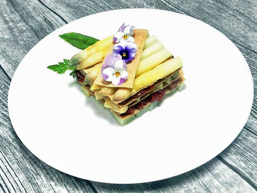 Auf einer Teller sind weiße Spargel angerichtet, die auf Tatar von Entenbrust liegen.