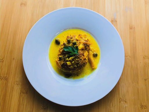 Ein Stück Fleisch auf einem Teller, rundherum gelbe Sauce. 