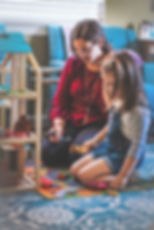 Jennifer Wisser-Stokes and a child playing together on the floor in her East Orlando therapy office