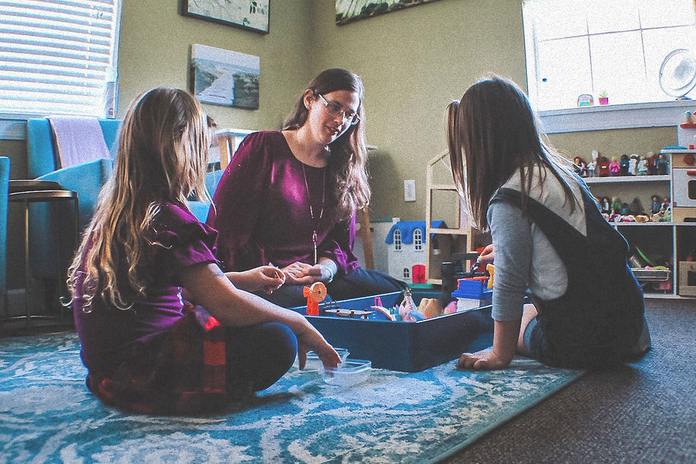 Jennifer Wisser-Stokes sitting on the floor with children during a play therapy session in Orlando